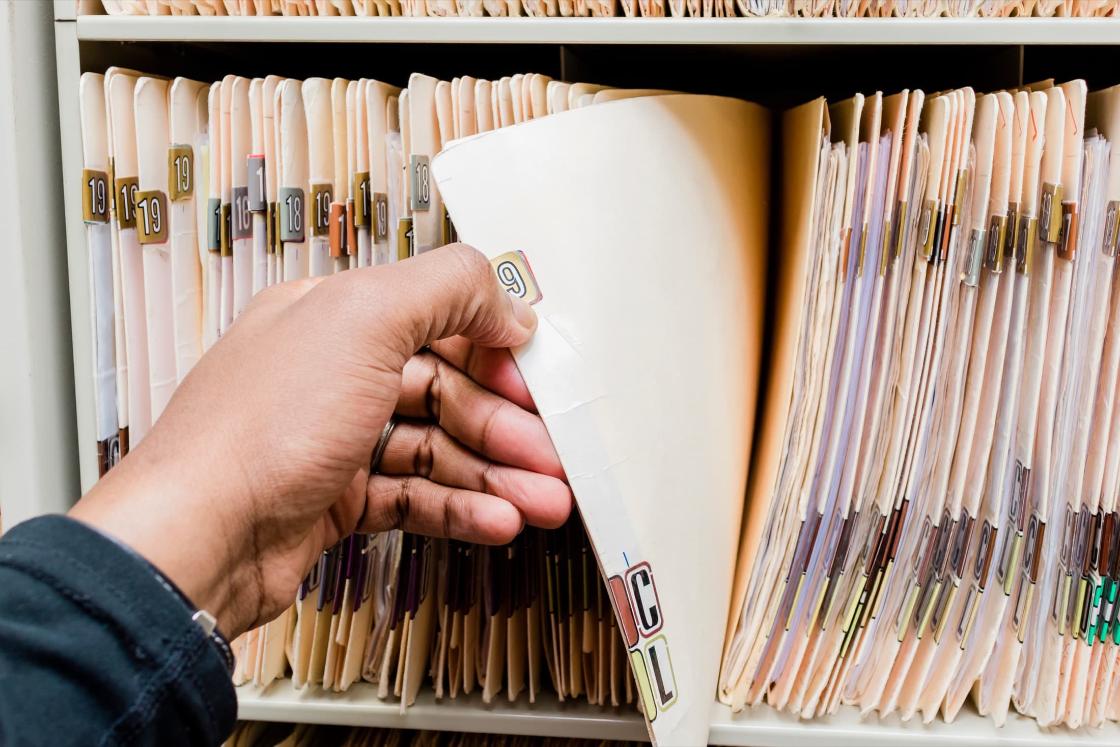An MRC specialist retrieving a client medical record from the color-coded filing system